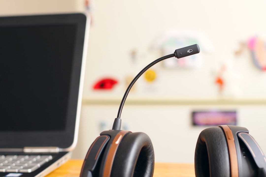 A headset next to a laptop computer on a desk