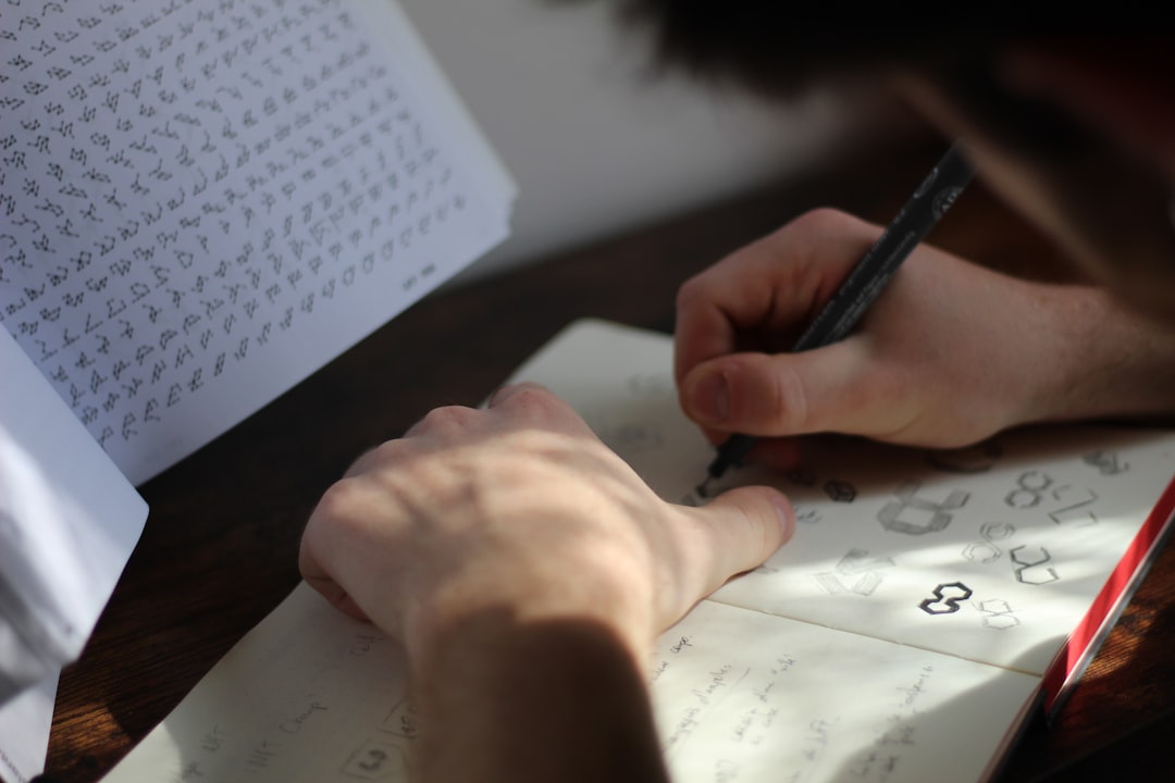 A hand sketching a logo design with a pen on paper